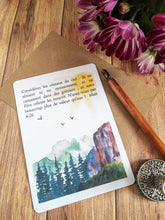 Charger l'image dans la galerie, Carte postale aquarelle représentant une montagne paisible avec des sapins au premier plan, la montagne derrière un soleil délicat et trois oiseaux volant dans le ciel. Le verset biblique Matthieu 6:26 "Regardez les oiseaux du ciel : ils ne sèment ni ne moissonnent, et ils ne ramassent rien dans des greniers ; cependant votre Père céleste les nourrit. N'êtes-vous pas beaucoup plus précieux qu'eux ?" est inscrit sur la carte.